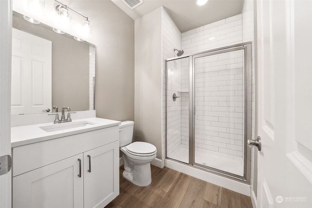 full bathroom with a stall shower, vanity, toilet, and wood finished floors