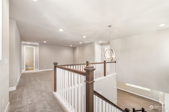 corridor featuring recessed lighting, baseboards, a notable chandelier, and an upstairs landing