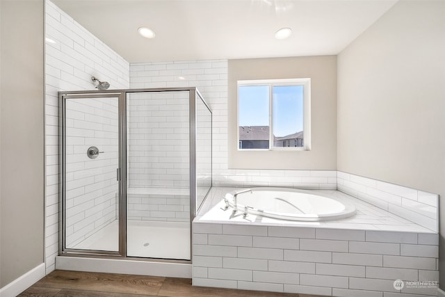 full bathroom with a garden tub, a shower stall, baseboards, and wood finished floors