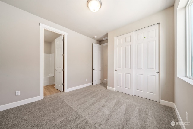 unfurnished bedroom featuring a closet, carpet flooring, ensuite bath, and baseboards