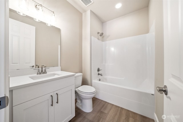 full bathroom featuring toilet, wood finished floors, vanity, visible vents, and  shower combination