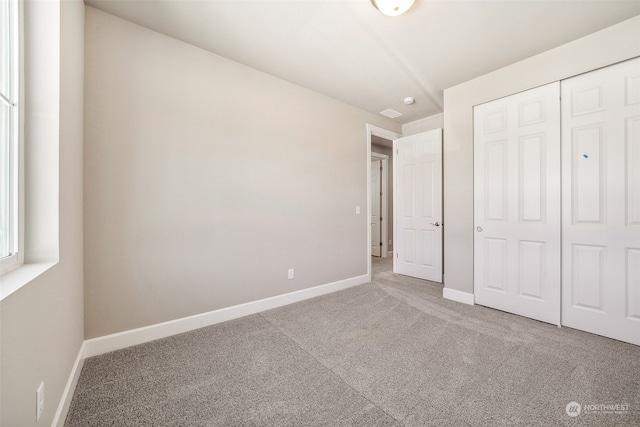 unfurnished bedroom with carpet, a closet, and baseboards