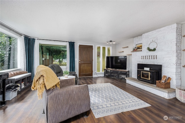 living room featuring a textured ceiling, dark hardwood / wood-style flooring, and a healthy amount of sunlight