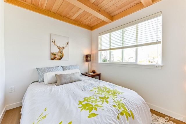 bedroom with wooden ceiling, wood finished floors, baseboards, and beam ceiling