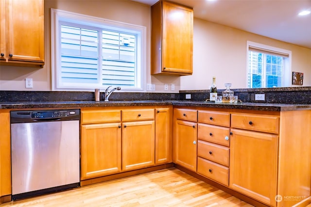 kitchen featuring dishwasher, dark stone countertops, sink, and light wood-type flooring