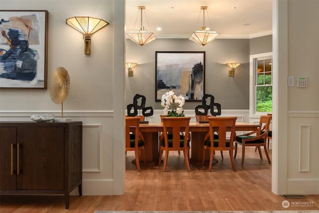 dining area with ornamental molding and light hardwood / wood-style flooring