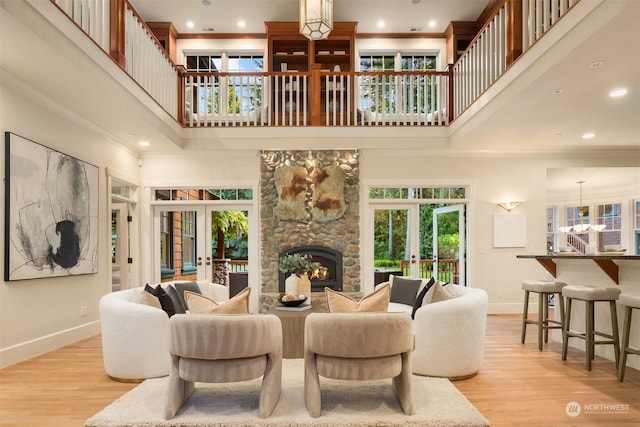 living room with french doors, a towering ceiling, and light hardwood / wood-style flooring