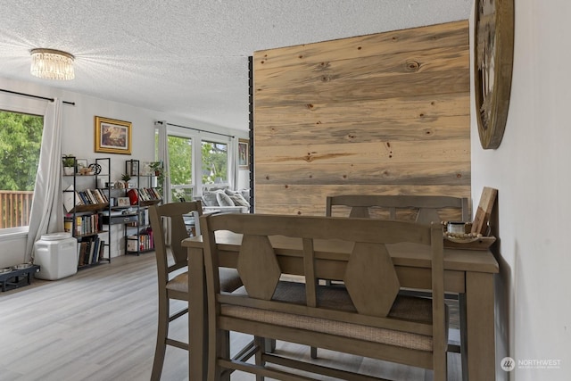 dining area with wooden walls, a textured ceiling, and hardwood / wood-style flooring