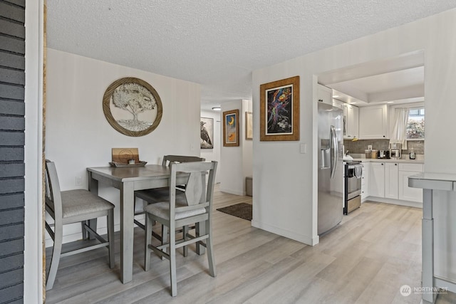 dining area featuring light hardwood / wood-style floors and a textured ceiling