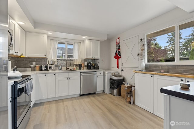 kitchen featuring backsplash, sink, light hardwood / wood-style flooring, appliances with stainless steel finishes, and white cabinetry