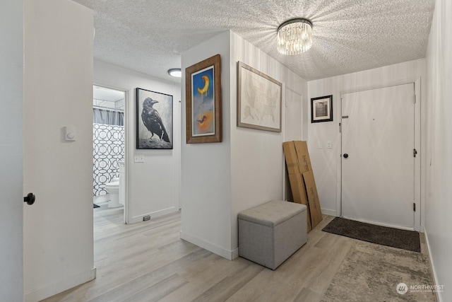 foyer featuring light hardwood / wood-style floors, a textured ceiling, and a notable chandelier