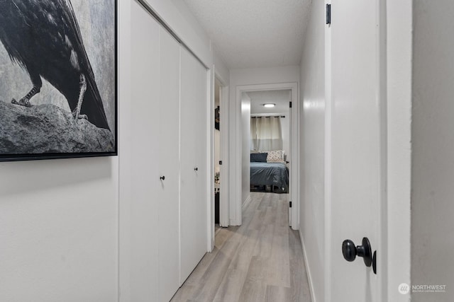 hall featuring light hardwood / wood-style floors and a textured ceiling