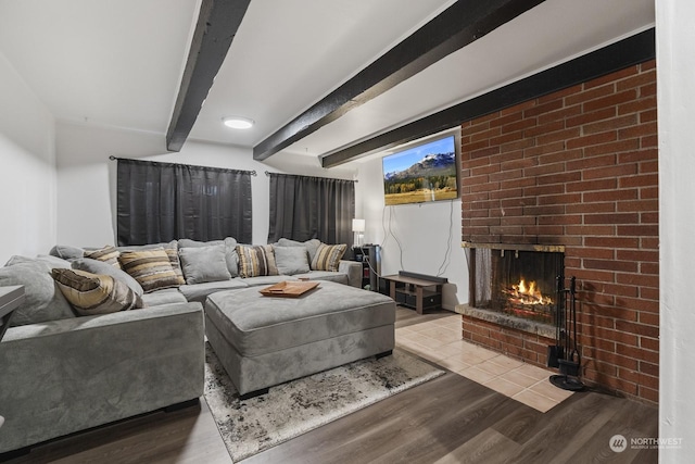 living room with beam ceiling, light hardwood / wood-style floors, and a brick fireplace