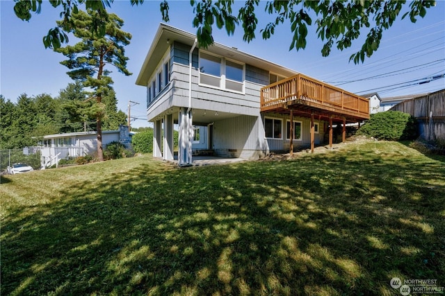 rear view of property featuring a patio, a lawn, and a wooden deck