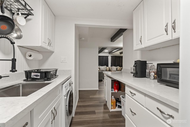 kitchen with dark wood-type flooring, sink, beam ceiling, white cabinetry, and washer / clothes dryer