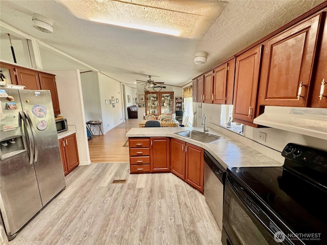 12 Moonlight Dr, Oroville, WA 98844 - kitchen with appliances with stainless steel finishes, under cabinet range hood, a peninsula, a sink, and a textured ceiling