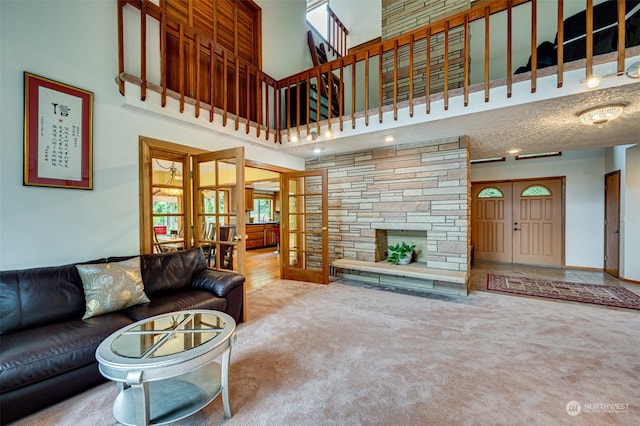 living room with carpet flooring, a towering ceiling, a stone fireplace, and french doors