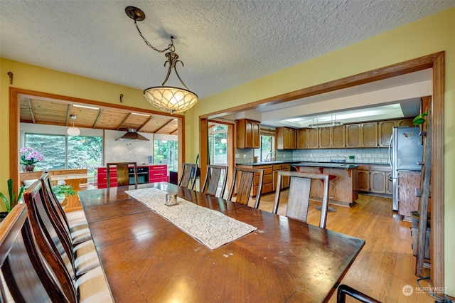 dining area with plenty of natural light, light hardwood / wood-style floors, and a textured ceiling