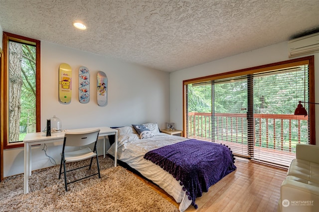 bedroom featuring wood-type flooring, an AC wall unit, and a textured ceiling