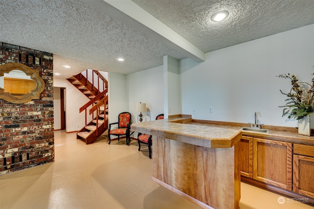 kitchen featuring sink, a textured ceiling, and brick wall