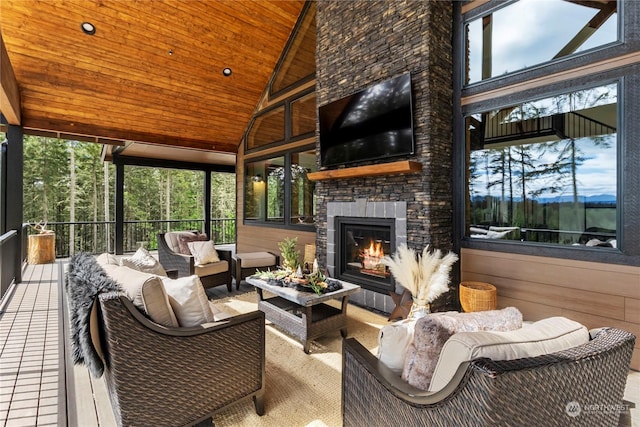 sunroom featuring a wealth of natural light, lofted ceiling, wood ceiling, and an outdoor stone fireplace