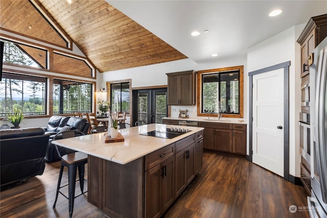 kitchen with black electric stovetop, dark hardwood / wood-style flooring, wood ceiling, a kitchen island, and a breakfast bar area