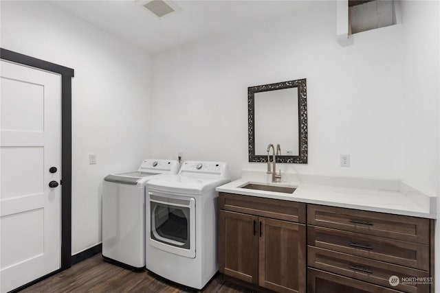 washroom featuring washing machine and dryer, sink, cabinets, and dark hardwood / wood-style floors