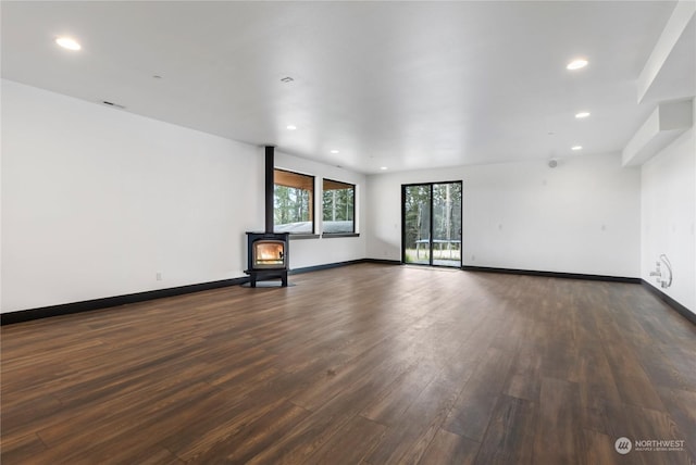 unfurnished living room with a wood stove and dark wood-type flooring