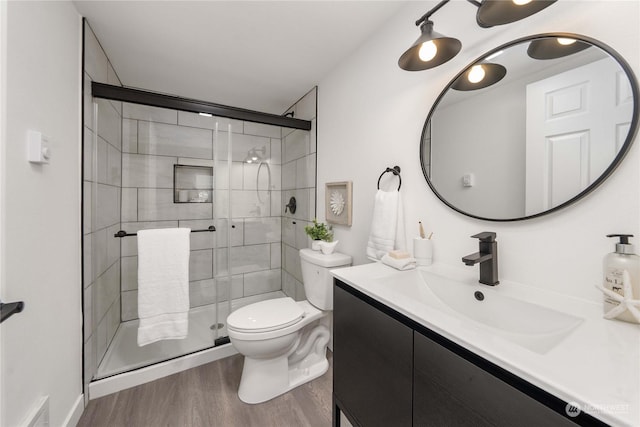 bathroom featuring wood-type flooring, vanity, toilet, and a shower with door