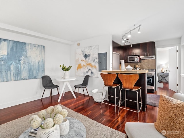 kitchen featuring tasteful backsplash, dark hardwood / wood-style floors, extractor fan, dark brown cabinets, and appliances with stainless steel finishes