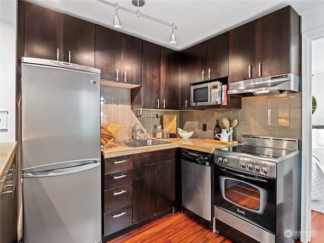 kitchen featuring ventilation hood, sink, wood-type flooring, and stainless steel appliances