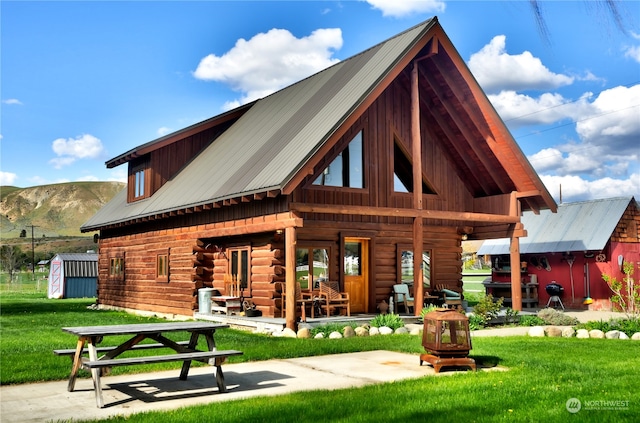 rear view of property featuring a patio, a storage unit, a mountain view, and a yard