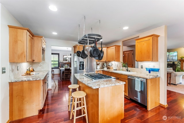 kitchen featuring a center island, stainless steel appliances, dark wood-type flooring, and a sink