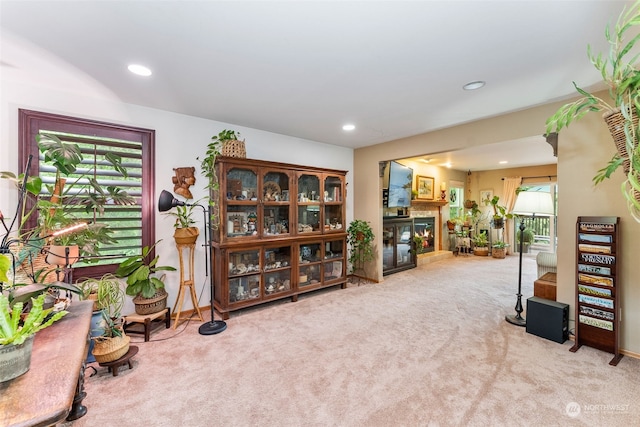 living area featuring recessed lighting, light carpet, and a glass covered fireplace