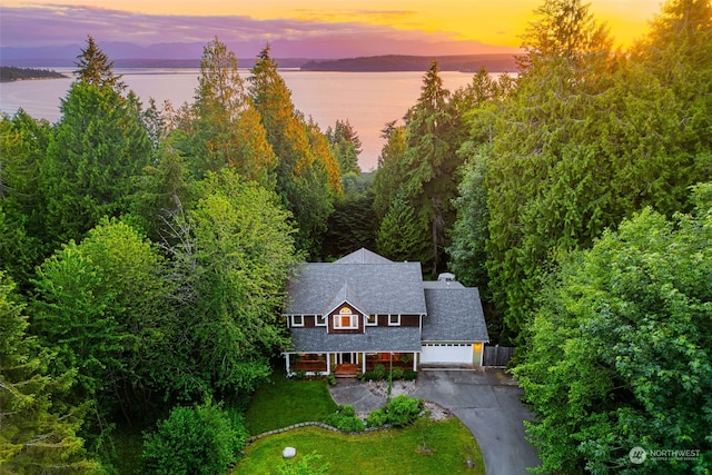 aerial view at dusk featuring a water view
