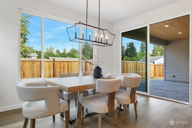 dining area with hardwood / wood-style floors, a healthy amount of sunlight, and a chandelier