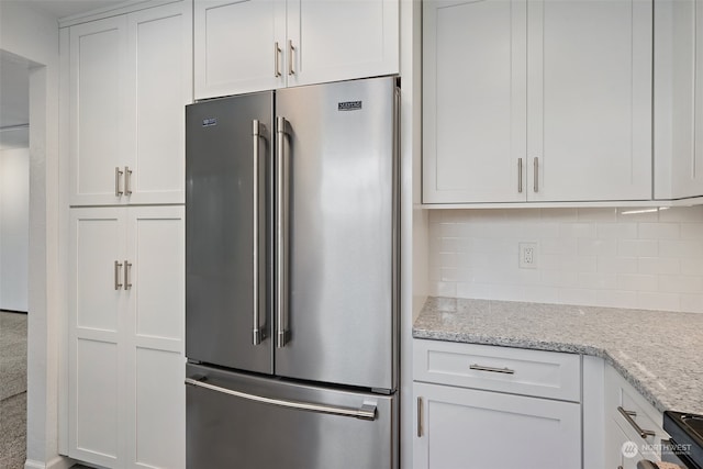 kitchen featuring backsplash, light stone counters, electric range, high end fridge, and white cabinetry