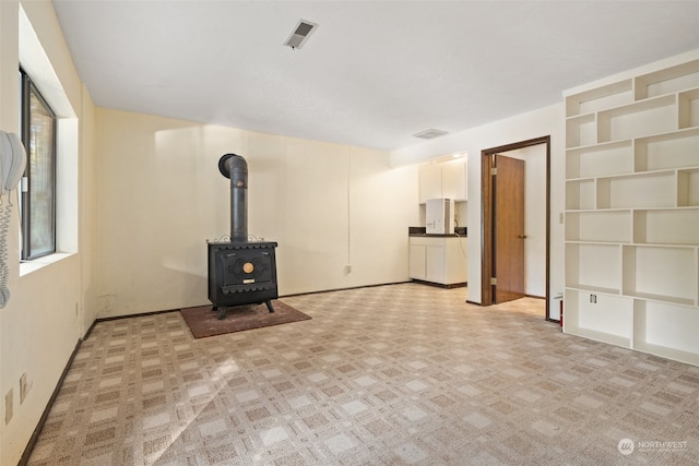 unfurnished living room featuring a wood stove and visible vents