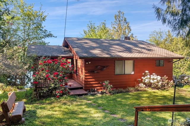 exterior space with a lawn, a wooden deck, and roof with shingles