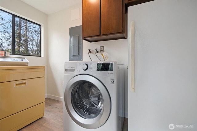 clothes washing area featuring independent washer and dryer, electric panel, cabinet space, light wood finished floors, and baseboards