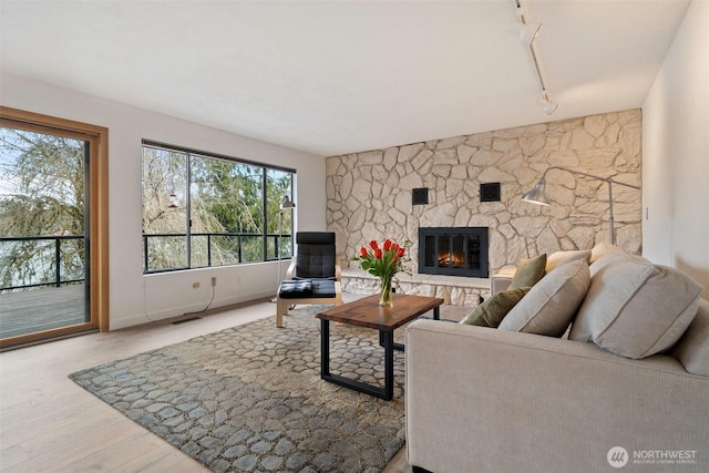 living area featuring visible vents, baseboards, a fireplace, rail lighting, and wood finished floors