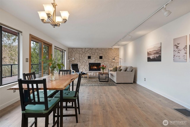 dining space with visible vents, a fireplace, baseboards, and wood finished floors