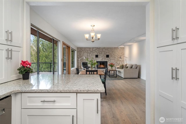 kitchen with a stone fireplace, a peninsula, an accent wall, and white cabinetry