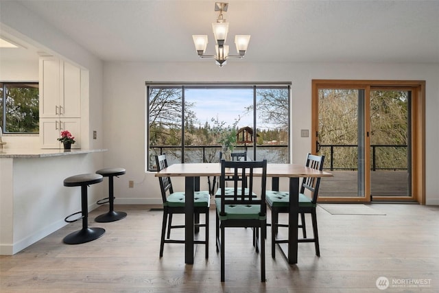 dining area with an inviting chandelier, baseboards, and light wood-style floors