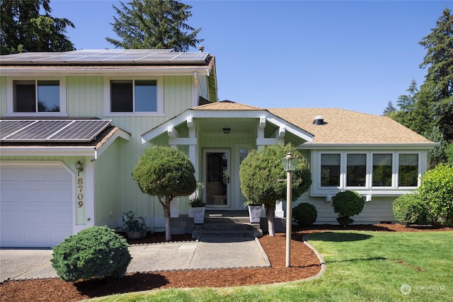 view of front of home featuring a front yard, solar panels, and a garage