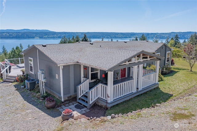 view of front facade featuring a water and mountain view, cooling unit, and covered porch