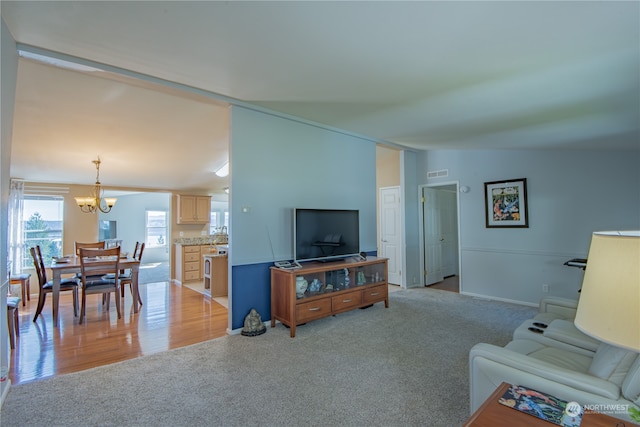 living room with light colored carpet, an inviting chandelier, and lofted ceiling