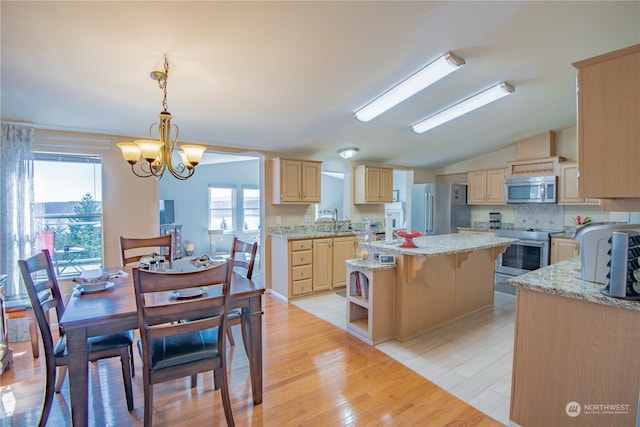 kitchen featuring a center island, a notable chandelier, a healthy amount of sunlight, and appliances with stainless steel finishes