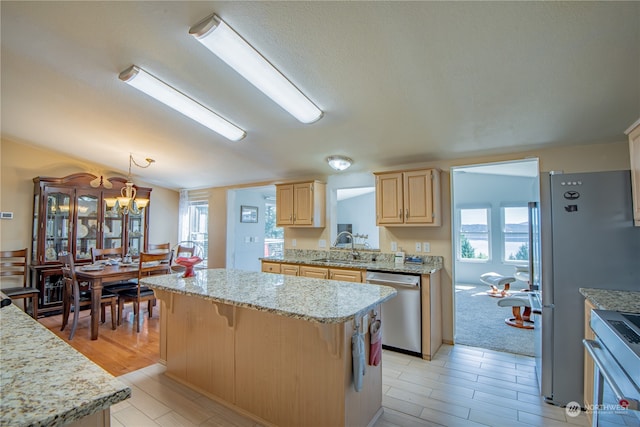 kitchen with appliances with stainless steel finishes, light brown cabinetry, decorative light fixtures, a kitchen island, and plenty of natural light