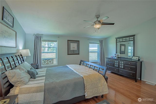 bedroom with ceiling fan, light hardwood / wood-style floors, and vaulted ceiling